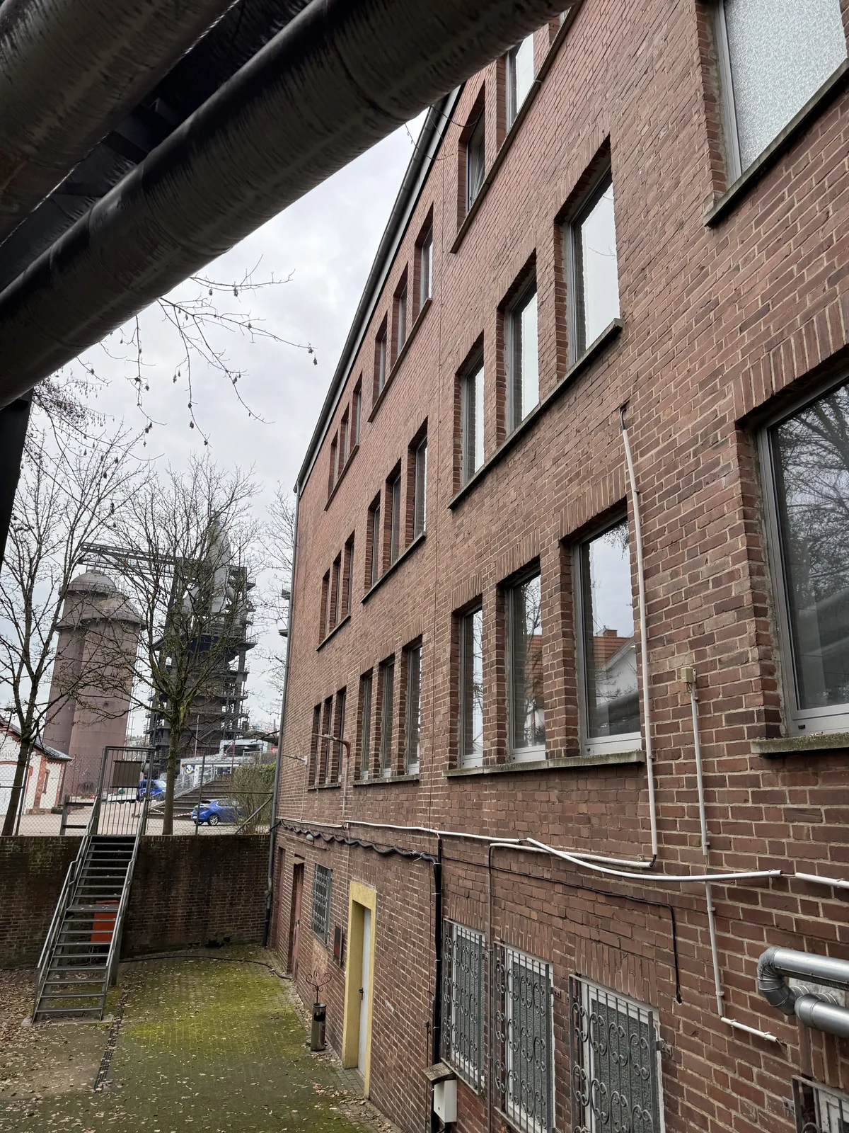 Mehrgeschossiges Bürogebäude mit Backsteinfassade, Fenstern und außenliegenden Leitungen