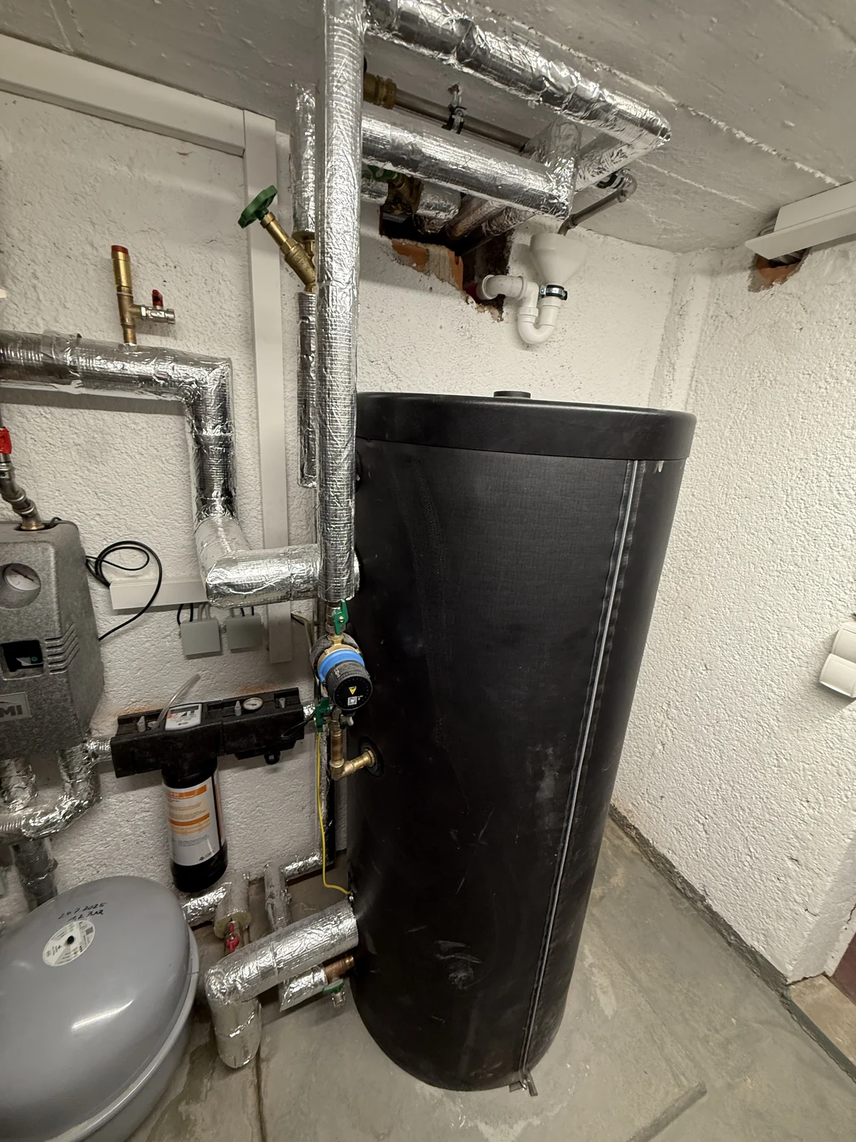 Speicher mit gedämmten Leitungen und Armaturen in einem Heizraum