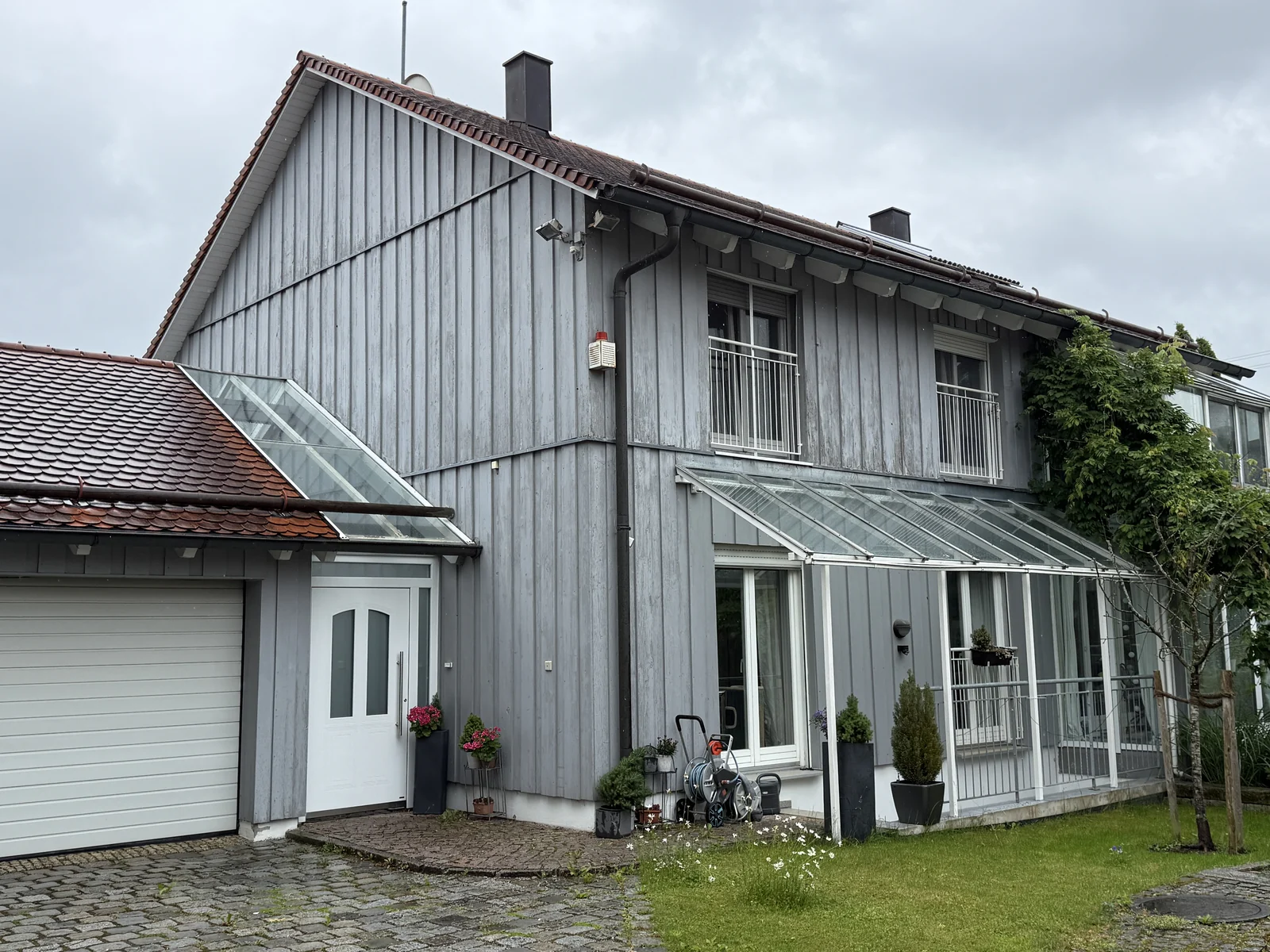 Wohnhaus mit Holzfassade, Satteldach und verglastem Anbau
