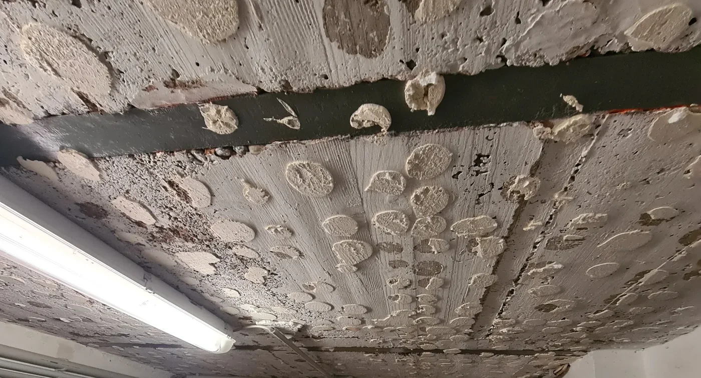 Nahaufnahme einer Kellerdecke mit Leuchte und Leitungen